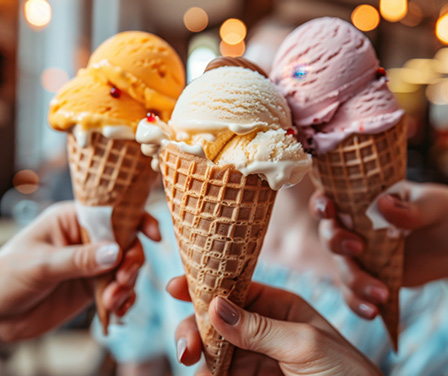 Three waffle cones with colorful scoops of ice cream held up together.